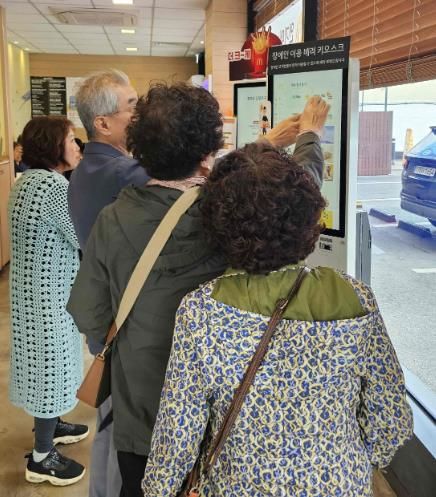 밀양시 삼문동 맥도날드 밀양DT점에서 열린 디지털 키오스크 문해교육 현장실습에 참여한 학습자들이 키오스크를 직접 조작하며 주문을 연습하고 있다.