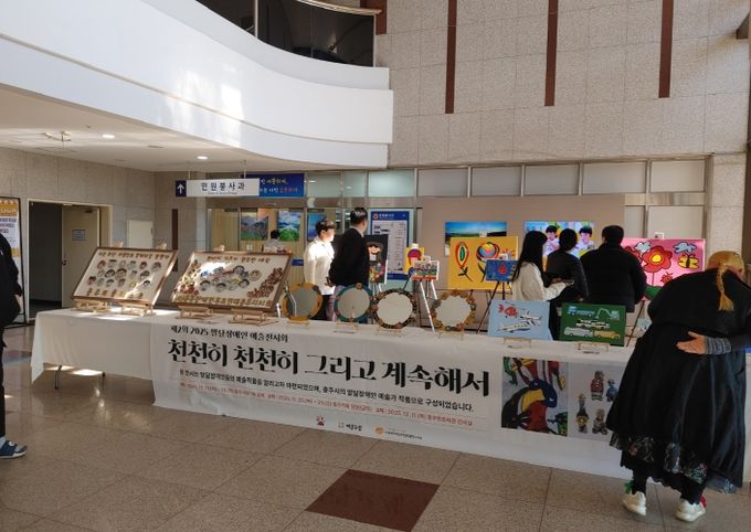 충주시청서 제2회 발달장애인 예술전시회 개최(시민들이 전시회 작품을 보고 있다)